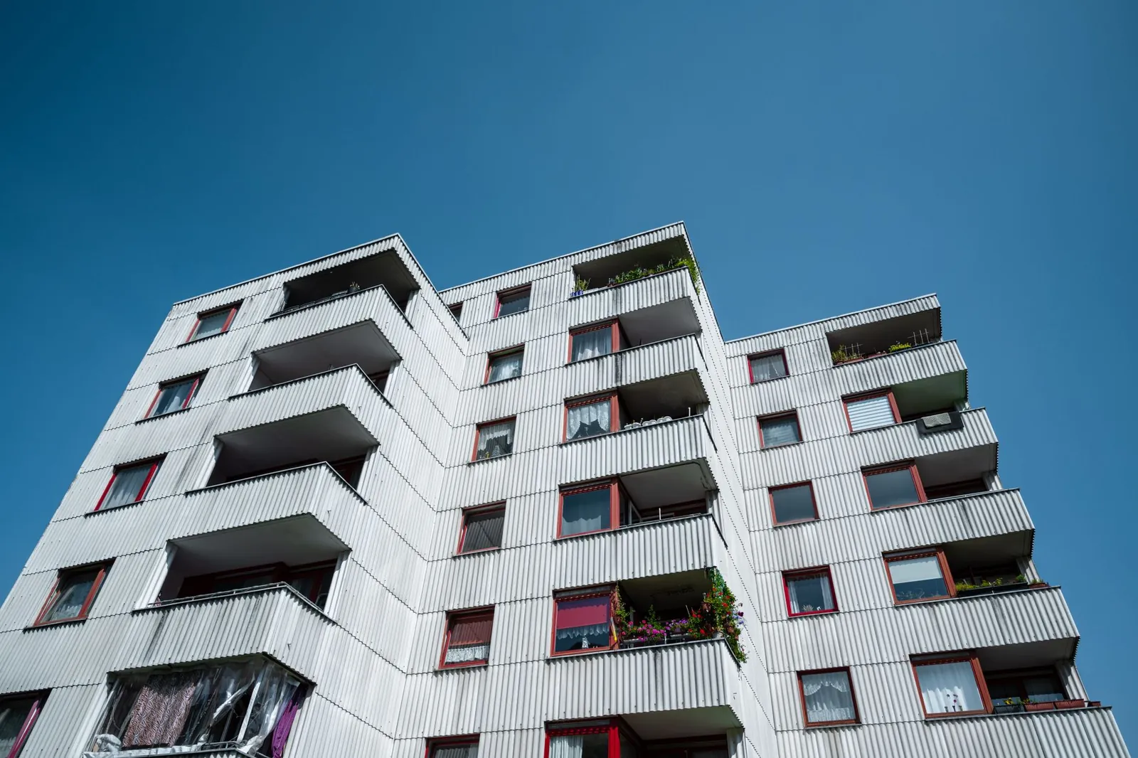 Fassade eines Mehrfamilienhauses mit Balkonen vor blauem Himmel
